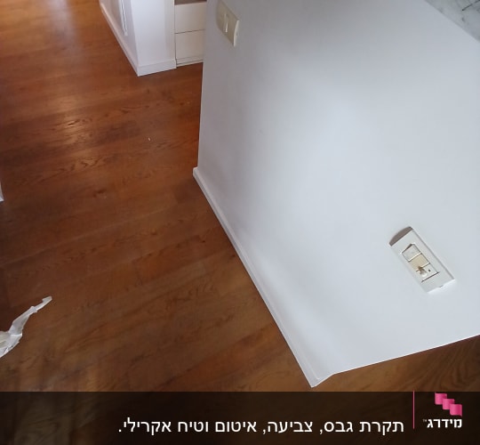 רצפת עץ עם קיר לבן ושקעים חשמליים